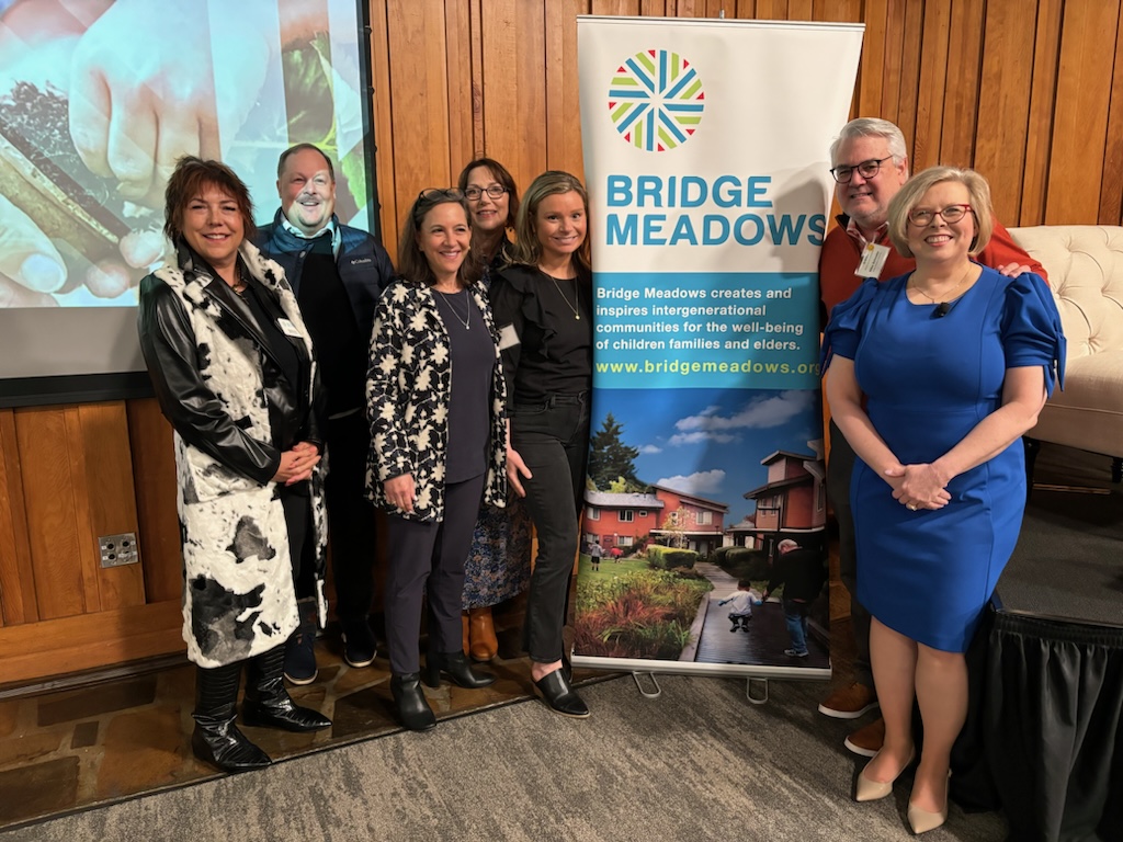 Staff pose with a banner about Bridge Meadows.