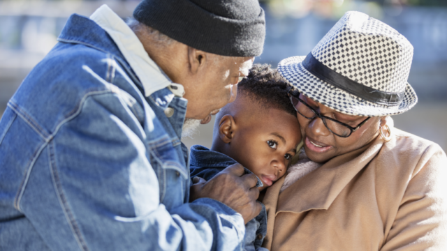 A Black grandmother and grandfather hold and comfort their grandchild