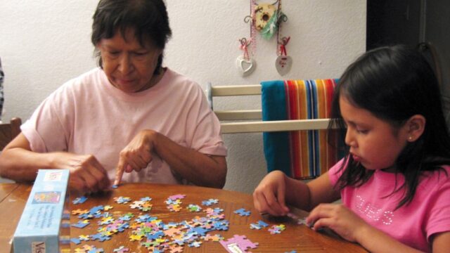 A Native grandmother and her granddaughter work on a puzzle together