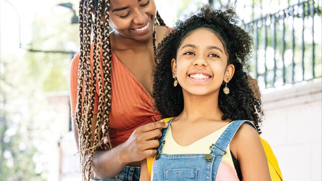 Mother smiling and standing next to her daughter